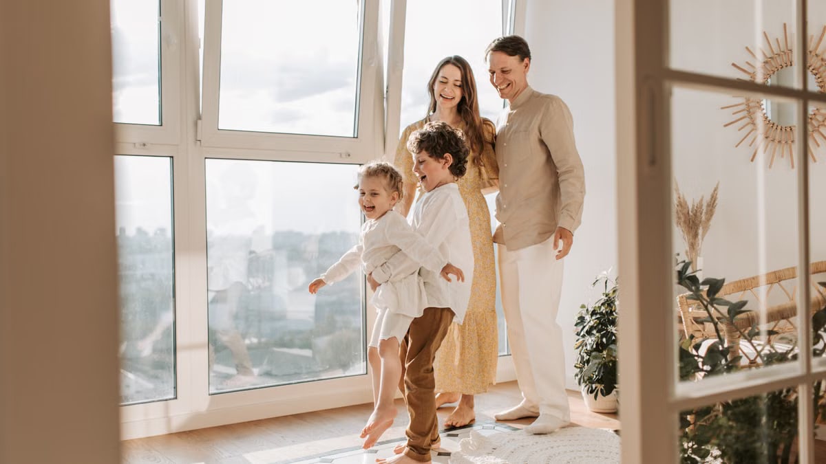 A joyful family of four enjoying time together in a bright, modern living room.